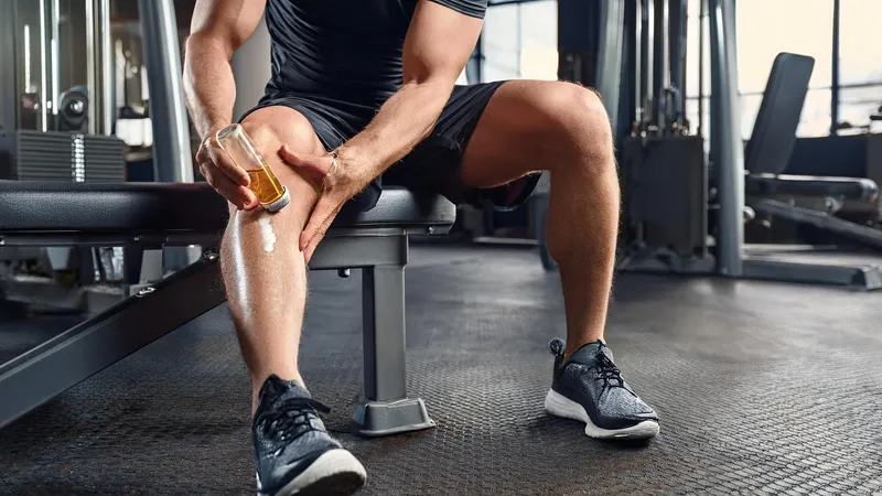 CBD Massage Oils for Pain Relief, Stress, Relaxation and Uplift | Broad Essentials A man at a gym applying a pain relief to his knees.